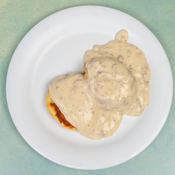 Biscuits and gravy, a classic breakfast dish from Ellen's Kitchen, on a white plate.
